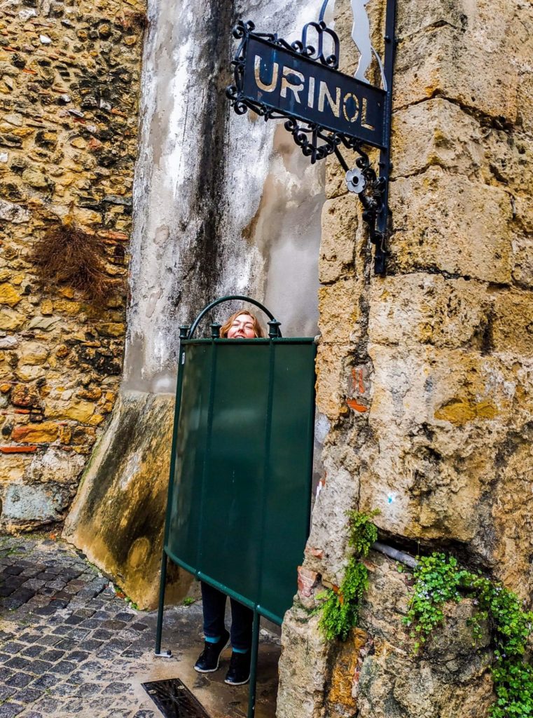 Outdoor urinal with a girl inside it.