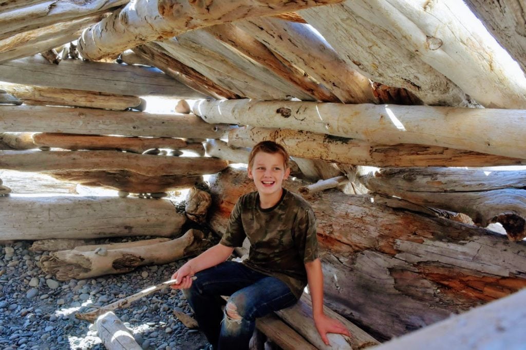 boy sitting inside fort on the beach