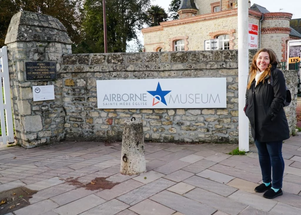 A woman standing next to the entrance to the airborne Museum